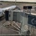 نمای هوایی از هواپیمای مسافربری شرکت رایان‌ایر پارک‌شده در باند فرودگاه منچستر در کنار جت‌بریج و پل مسافربری فرودگاه با لوگوی Manchester Airport.
