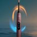مسواک برقی هوشمند Philips Sonicare به رنگ برنزی متالیک همراه با خطوط نورانی آبی و طلایی چرخان در اطراف سری مسواک