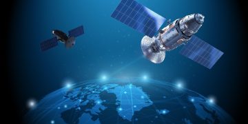 Two satellites with large solar arrays orbit a glowing blue Earth, illustrating space technology and communication links.