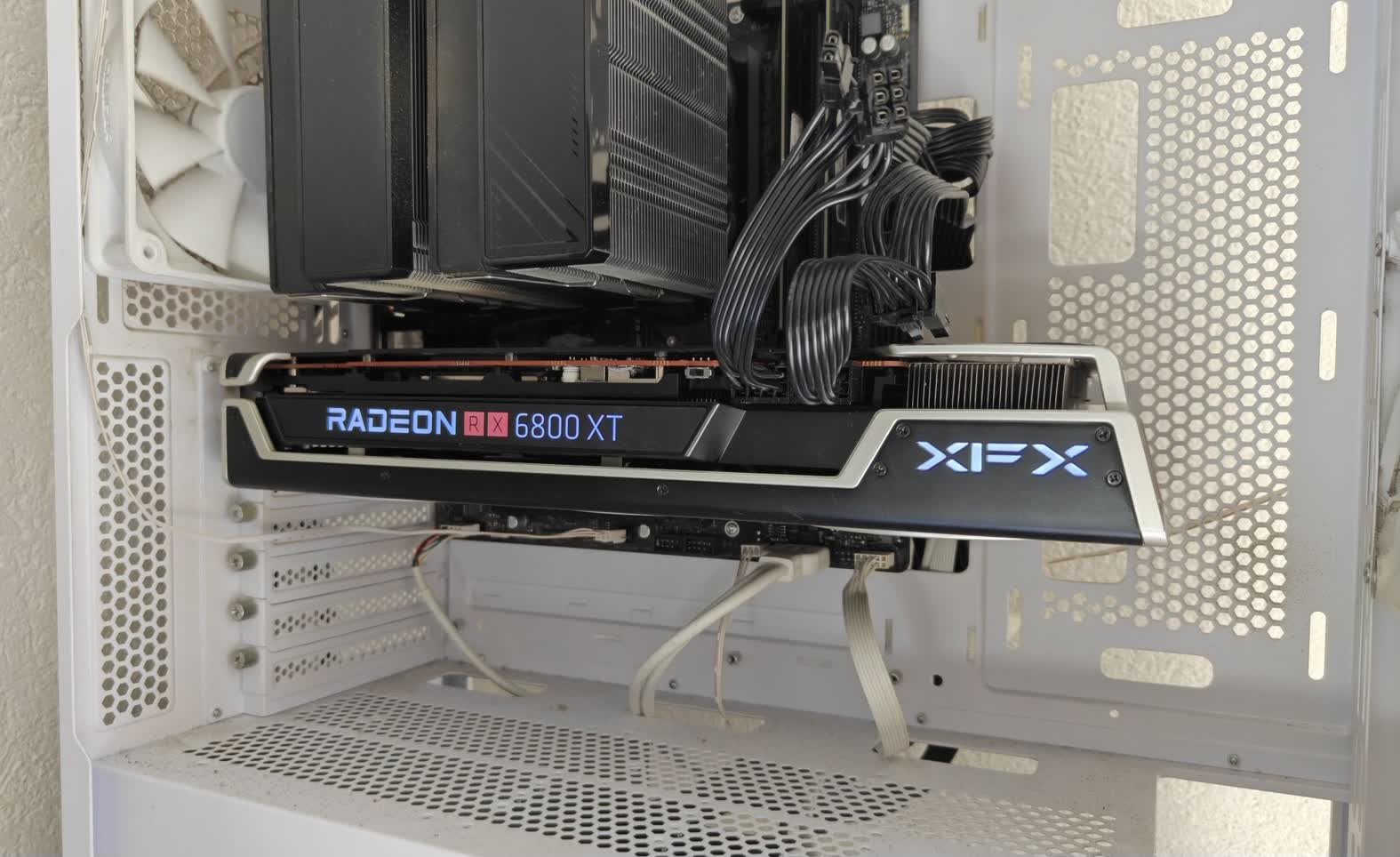 کارت گرافیک: XFX Radeon RX 6800 XT در یک برج کامپیوتر سفید با کابل های قابل مشاهده و یک فن خنک کننده در نزدیکی نصب شده است.