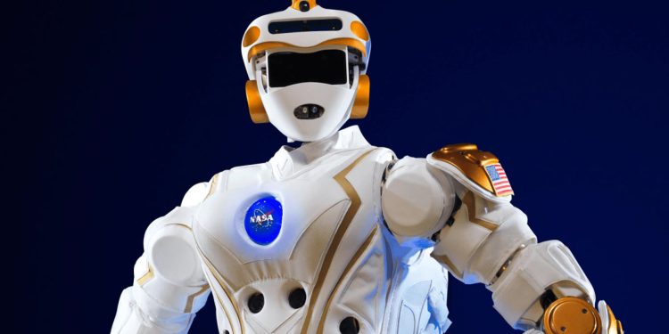 ناسا می خواهد ربات های انسان نما را به ماه بفرستد 1 NASA humanoid robot in white armor with orange joints and a visible NASA logo on the chest, posed against a dark blue background.