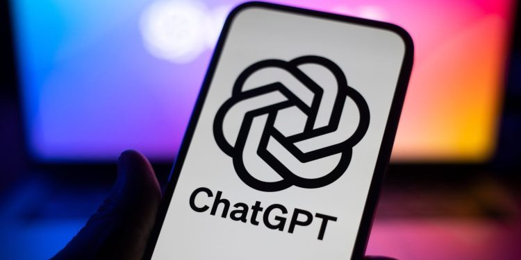 Card displaying the ChatGPT logo and name held in front of a blue‑pink neon background.