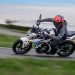 نگاه اول به موتورسیکلت BMW F 450 R 2027: مدلی سبک با تجهیزات پیشرفته 8 Motorcyclist in black gear and a red helmet leans into a sharp turn on a white sport bike along a road, with motion blur in the background.