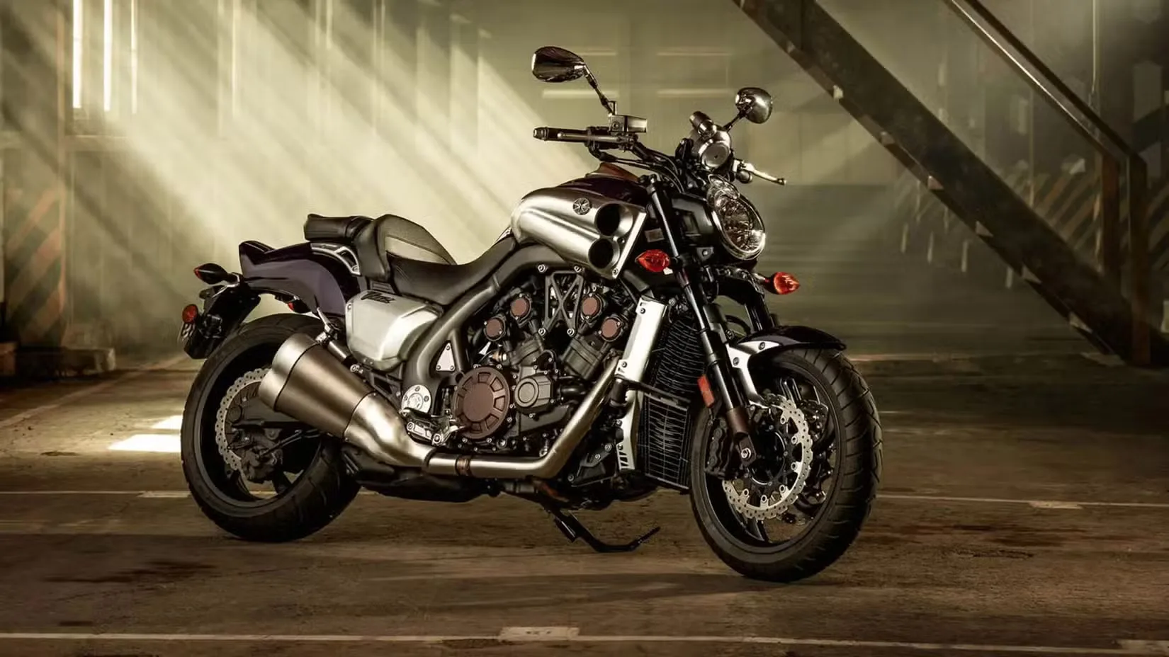 Sport motorcycle with a curvy silver exhaust and exposed engine, parked in a dim, industrial parking garage.