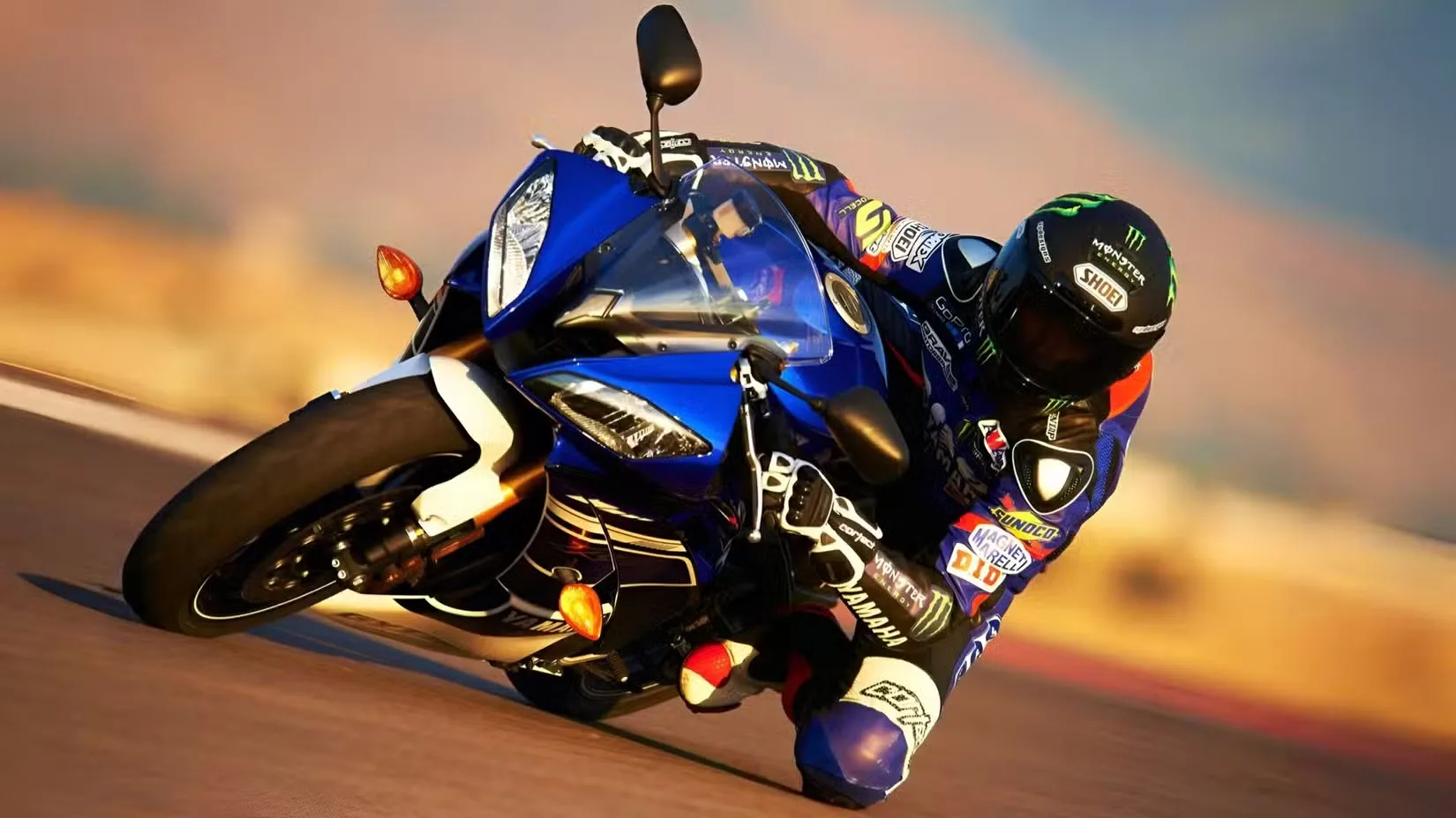 Racer in blue protective suit leaning into a curved turn on a blue sport motorcycle on a racetrack, helmeted and in motion