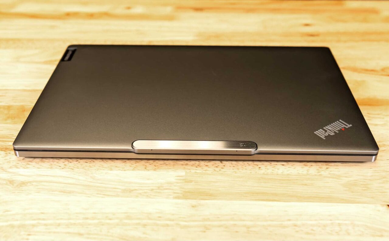 1000085047 لپ تاپ Lenovo ThinkPad مشکی بسته روی یک میز چوبی قرار گرفته است و نشان ThinkPad در گوشه درب آن قابل مشاهده است.