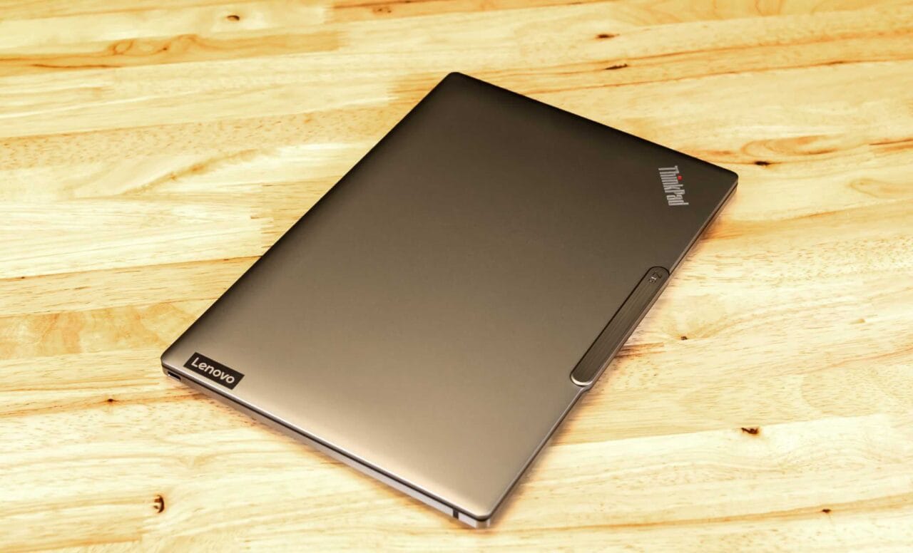 1000085853 لپتاپ ThinkPad Lenovo را روی یک سطح میز چوبی سبک، از گوشه بالا سمت چپ، بسته است.