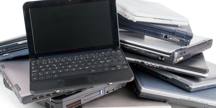 6 روش بسیار ساده برای استفاده مجدد از لپ تاپ خراب قدیمی 1 Pile of assorted laptops stacked in a heap, showing keyboards and side ports.