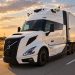 White semi-truck with trailer driving on a highway at sunset, emphasizing motion and warm sky colors.