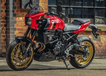 Red Suzuki sport motorcycle with gold wheels parked beside a brick storefront exterior.