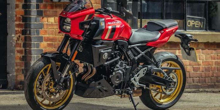 Red Suzuki sport motorcycle with gold wheels parked beside a brick storefront exterior.