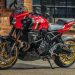 Red Suzuki sport motorcycle with gold wheels parked beside a brick storefront exterior.