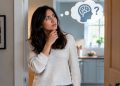 Woman standing in a doorway, stroking her chin and thinking, with a thought bubble showing a brain and a question mark above her.