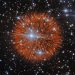 Brilliant supernova explosion in space with orange ejecta radiating outward among blue and white stars.