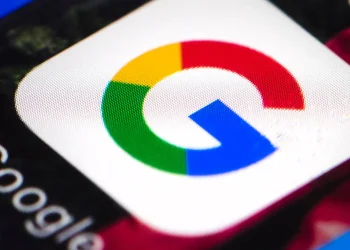 نمای نزدیک و باکیفیت از اپلیکیشن یا نماد گوگل (Google) با رنگ‌های چهارگانه مشخص روی صفحه نمایشگر و متن «Google» در کنار آن.