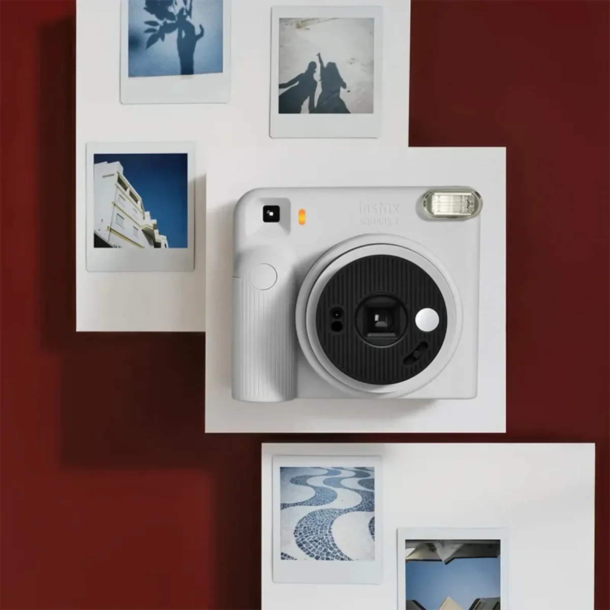 Fujifilm's Instax Square 2 camera was introduced with creative filters 6 White Instax Square SQ2 instant camera with black lens and silver flash in the center of the image, surrounded by four square printed photos on a crimson background.