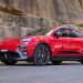 بررسی پورشه ماکان GTS 2026: خودرویی که شبیه سفینه فضایی است 8 Red Porsche SUV (Macan) parked on a paved road beside a rocky wall with greenery in the background.