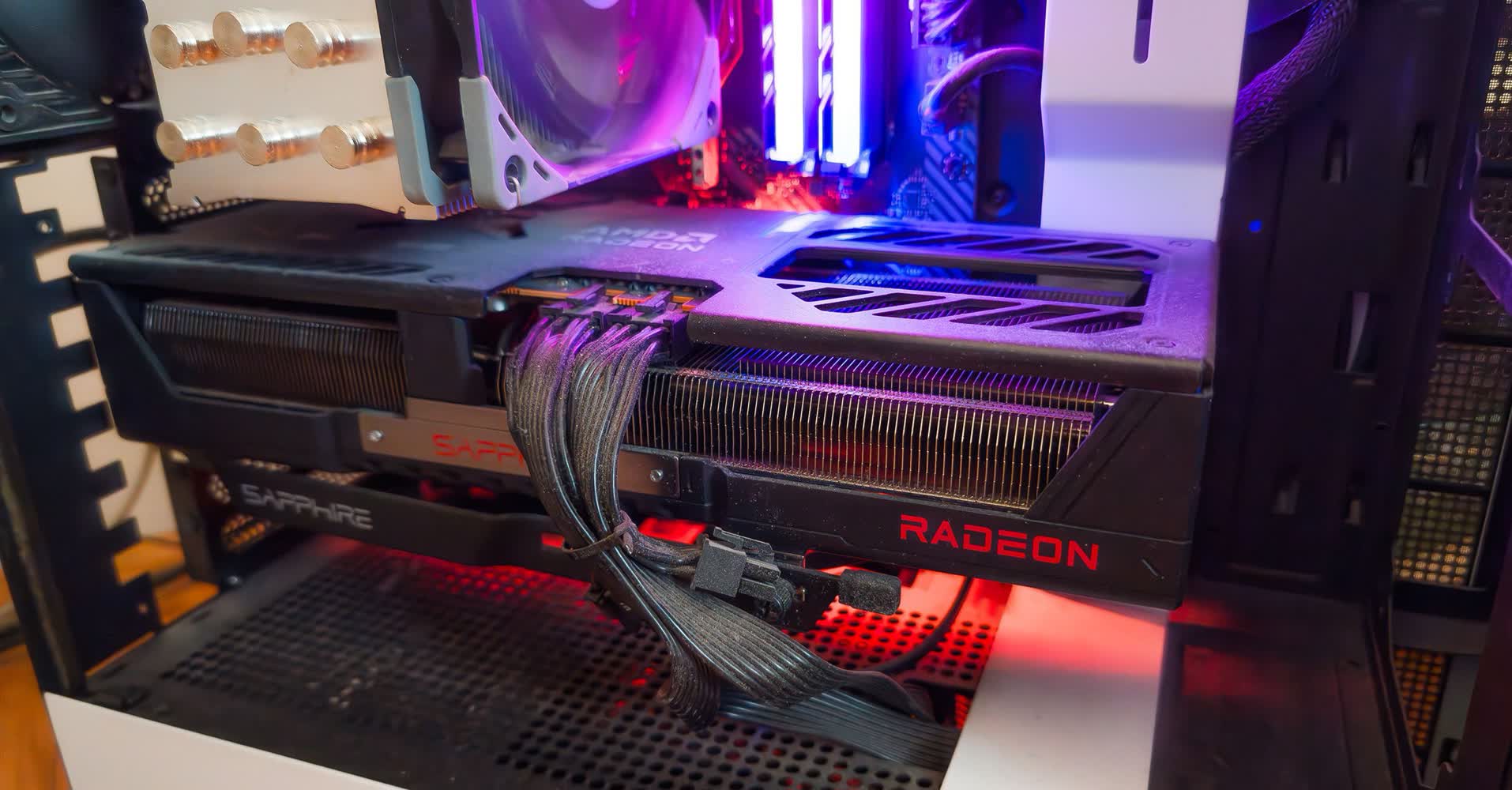 فضای داخلی یک رایانه بازی که کارت گرافیک Radeon با نشان‌واره قرمز، کابل‌های برق، و نور RGB را نشان می‌دهد.