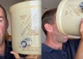 A man with short hair holds a large beige cylindrical storage tank with a side valve, shown in two frames side by side; he faces the camera in the left frame and drinks from the tank in the right frame (humorous prop).