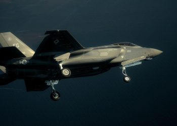 حسگر لیزری چینی موفق شد جنگنده F-35 آمریکایی را شناسایی کند 13 F-35 stealth fighter jet in mid-flight over the ocean with landing gear down, side view of a gray military aircraft.