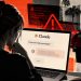 Person sits at a laptop open to a Claude chat window, with a sheriff’s office and officers in the background, implying online help near law enforcement.