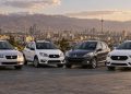 قیمت خودرو در بازار تهران; ساینا 1.8 میلیارد و ریرا 4.77 میلیارد تومان اعلام شد 17 Four sedans lined up on a parking area with a city skyline and snow-capped mountains in the distance at sunset.