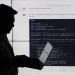 سیلوئت یک شخص در حال کار با لپ‌تاپ در برابر یک نمایشگر بزرگ که کدهای پایتون (PyTorch CNN) روی آن نمایش داده شده است.