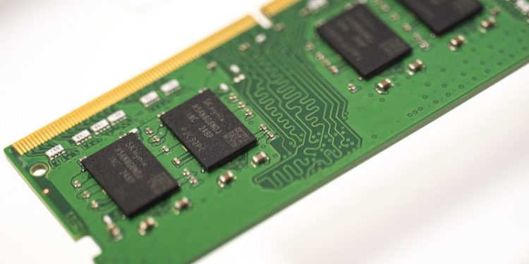 Green RAM module with a gold edge connector and black memory chips visible on a green PCB, seen at an angle.