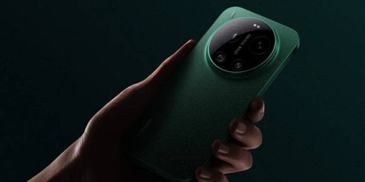 مشخصات گوشی لغو شده شیائومی 18 اولترا فاش شد 1 Hand holding a green smartphone with a large circular camera module on the back against a dark background, viewed from the side.