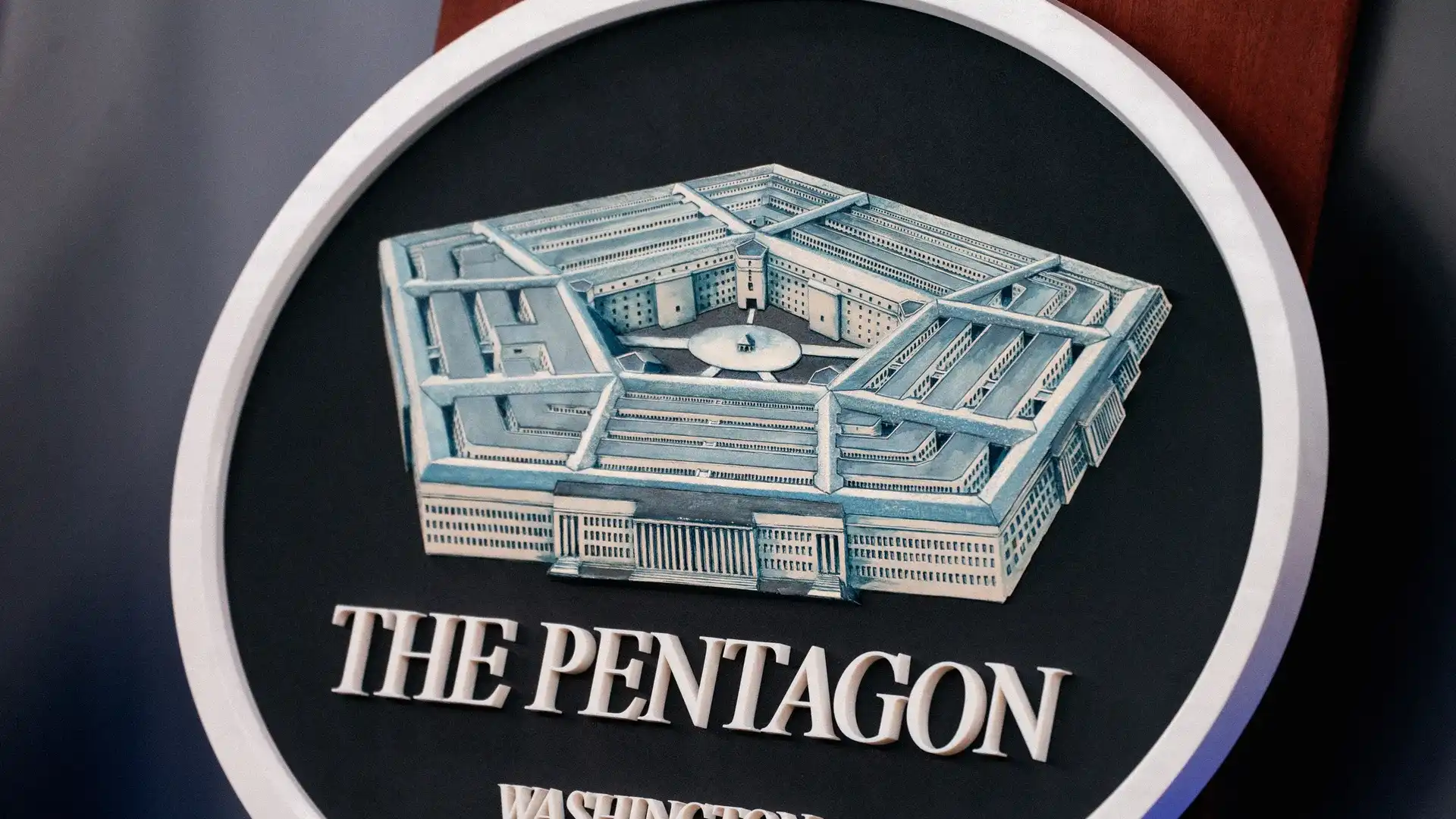 پنج ضلعی تابلوی دایرهای با مدل آبی پنتاگون در داخل یک نشان گرد با عبارت THE PENTAGON، واشنگتن دی سی